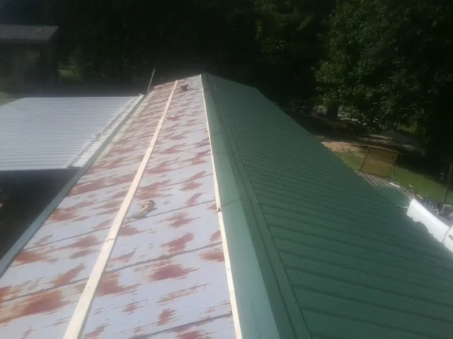 Old rusted panels beside newly installed green metal roofing — Wind Damage Roof Repair by Roofing Brothers in Port Charlotte