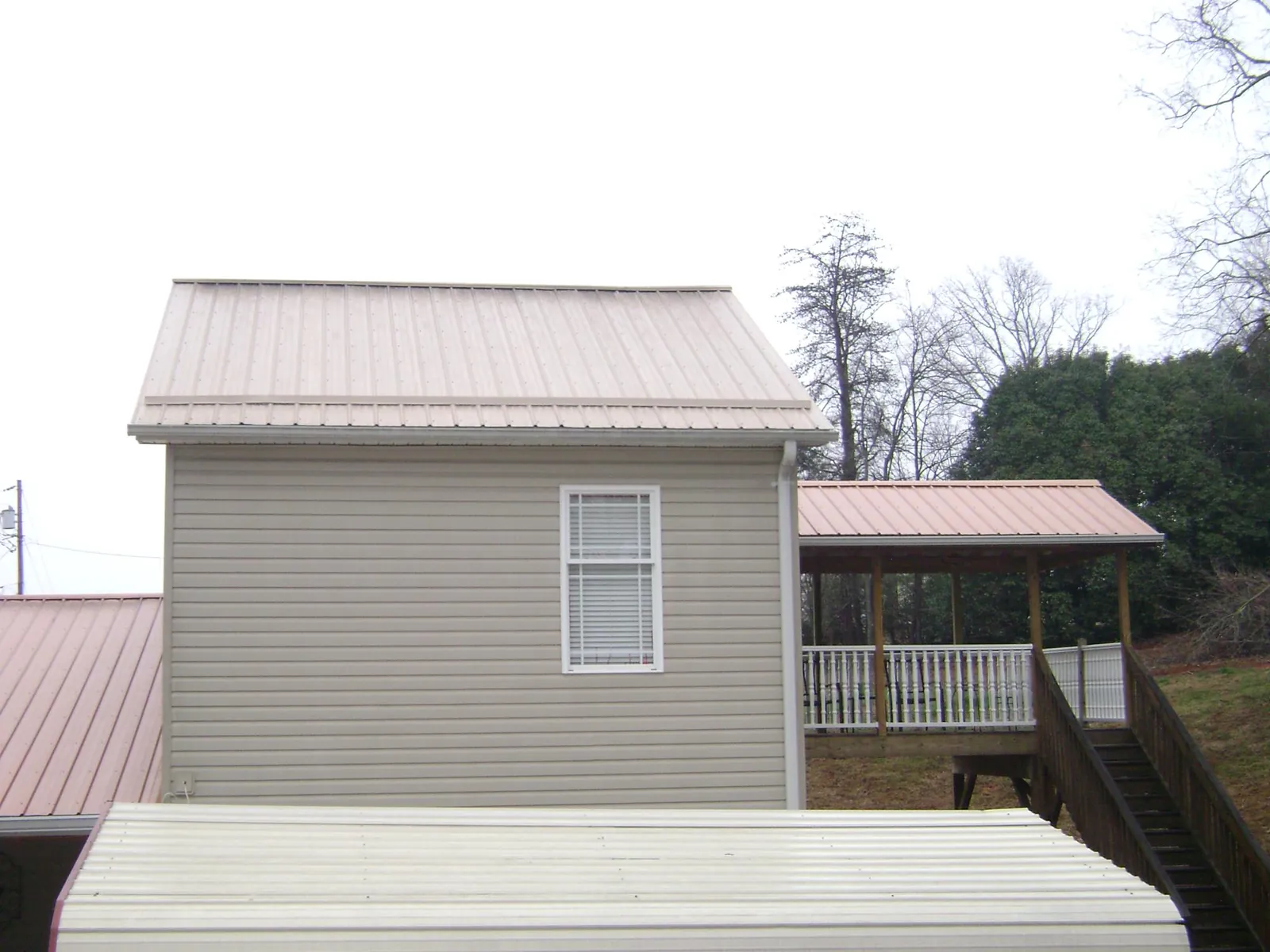 Tan metal roofs on a two story addition and attached porch, from a Roof Replacement job in Port Charlotte