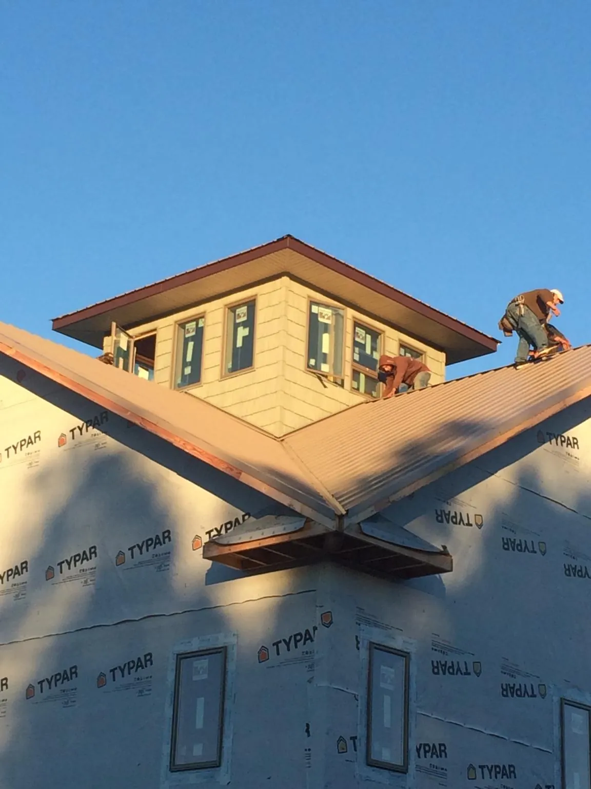 Roofers working around a rooftop cupola on a new metal roof at sunset — Roof Waterproofing in Port Charlotte by Roofing Brothers